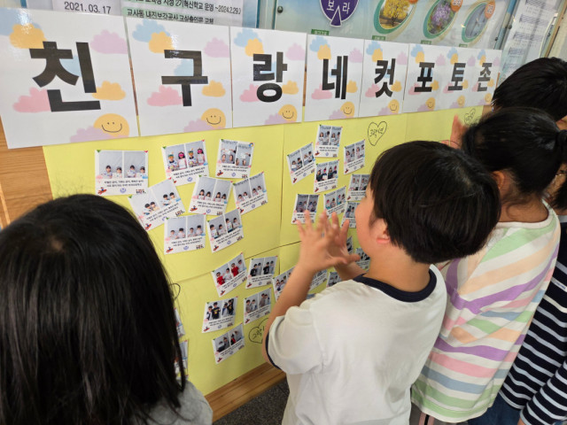 아이들이 장애 친구와 함께 ‘친구랑 네 컷 포토 행사’ 후 벽에 전시하고 있다